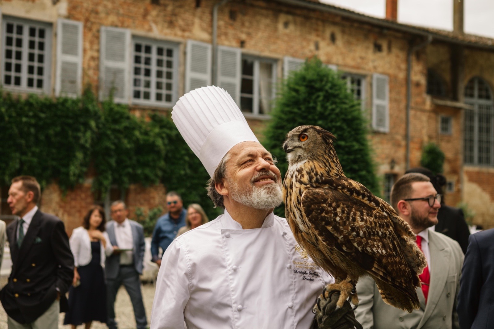 Chef cuisinier posant avec un hibou grand-duc devant le château