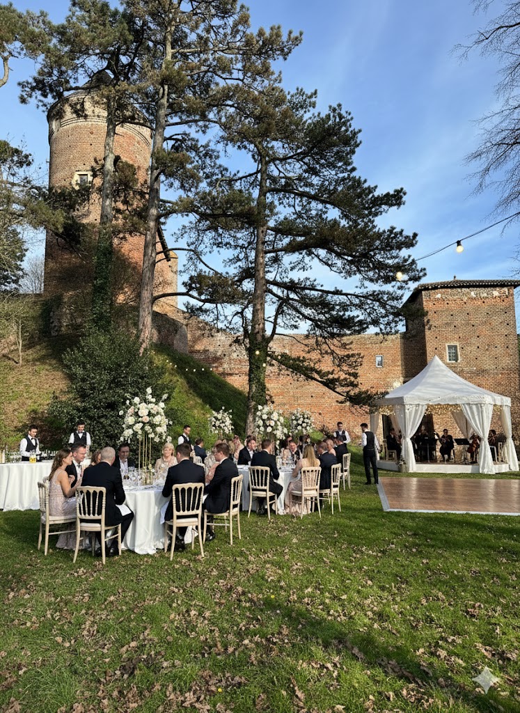 Dîner de mariage dressé dans le parc, devant le donjon illuminé