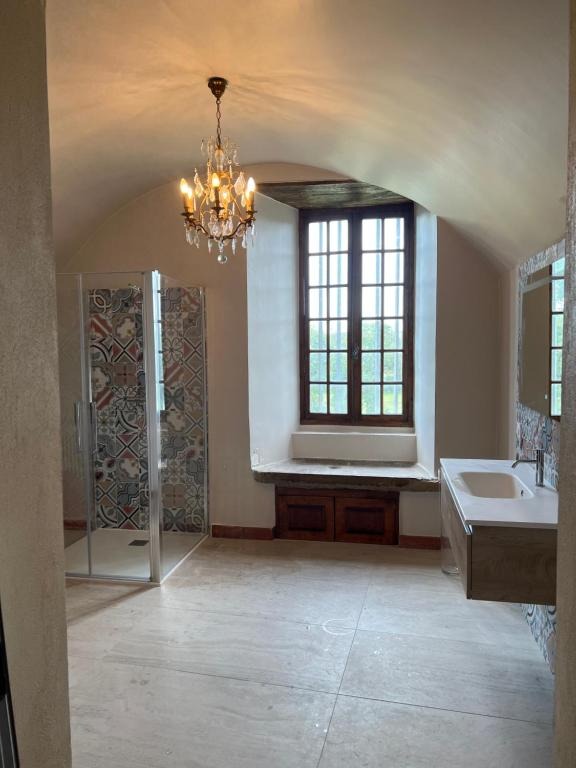 Salle de bain voûtée avec douche à l'italienne, carreaux de ciment et lustre
